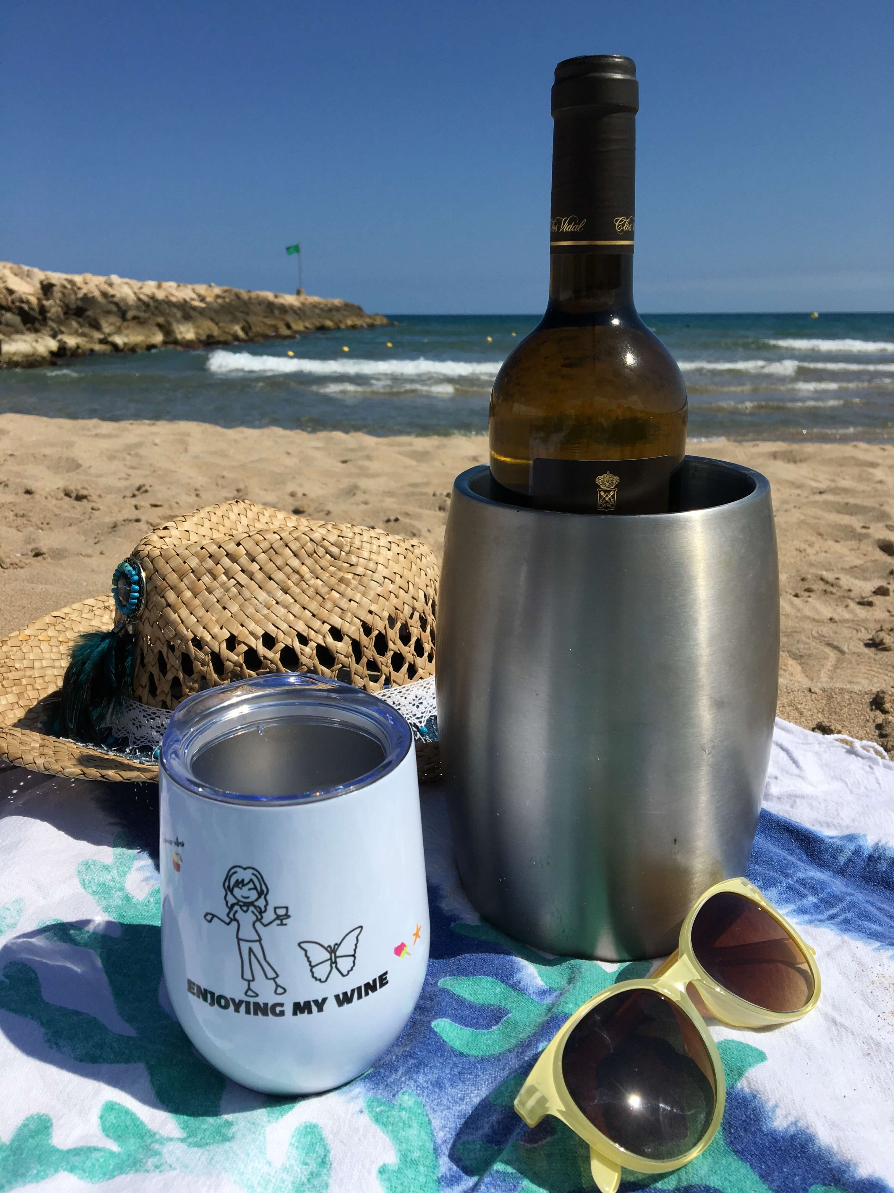 Njuter av en dag på stranden med vin och en vinbägare.