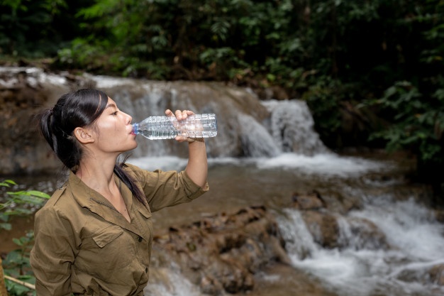 Kvinna som dricker vatten i skogen